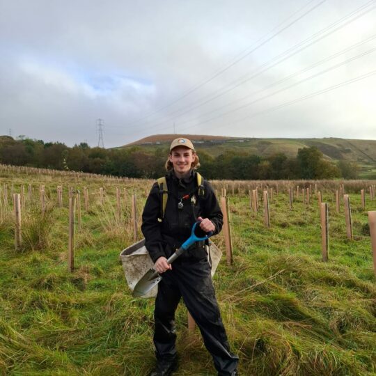 Man holding spade in field planting trees