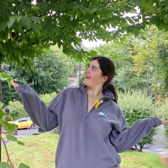 Girl posing under tree in grey fleece