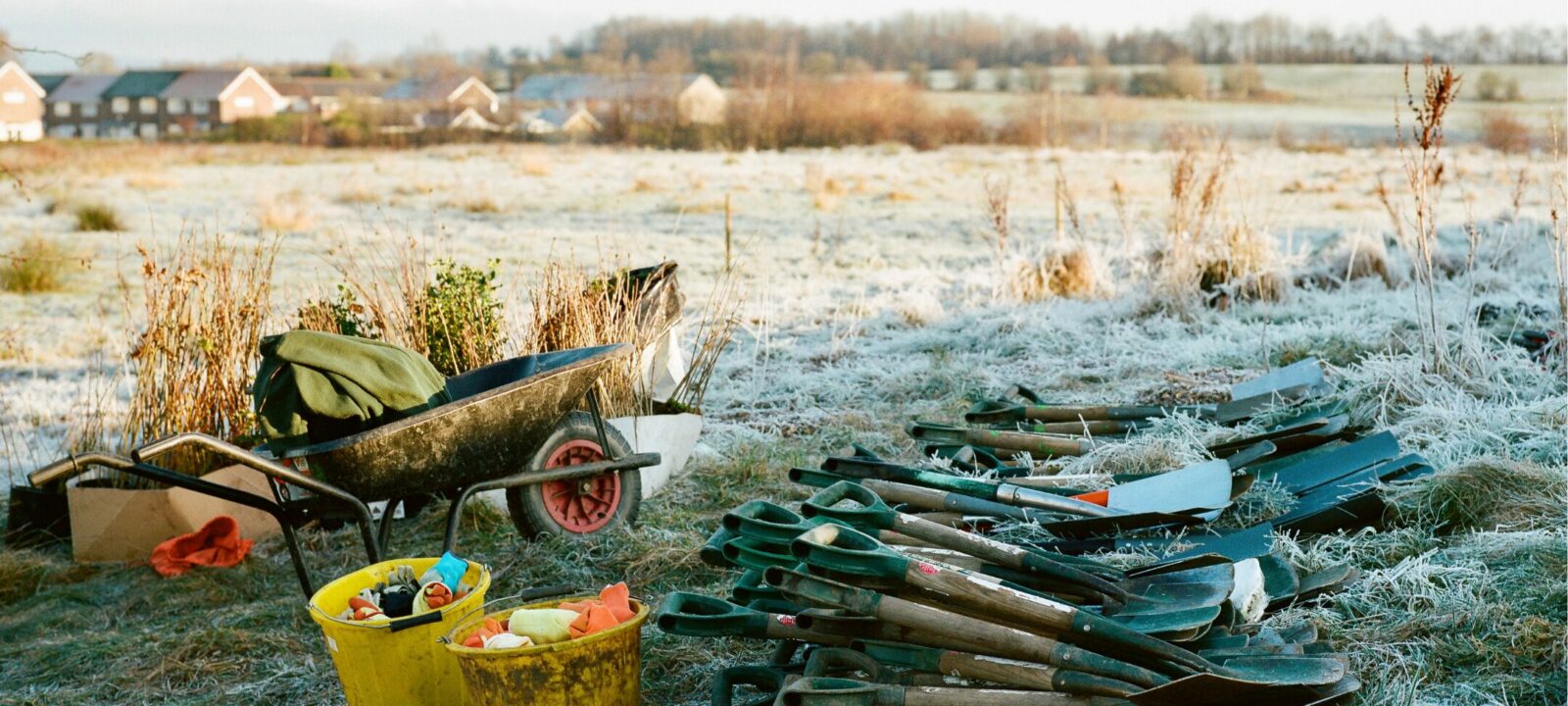 Wheelbarrow, buckets, bundle of spades, and whips.