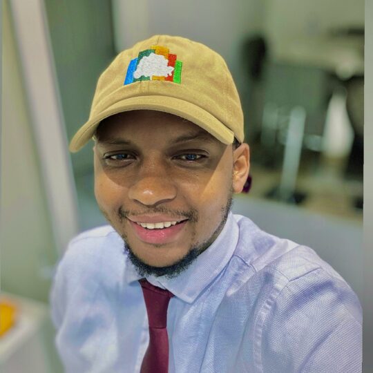 Man smiling in shirt and tie and cap