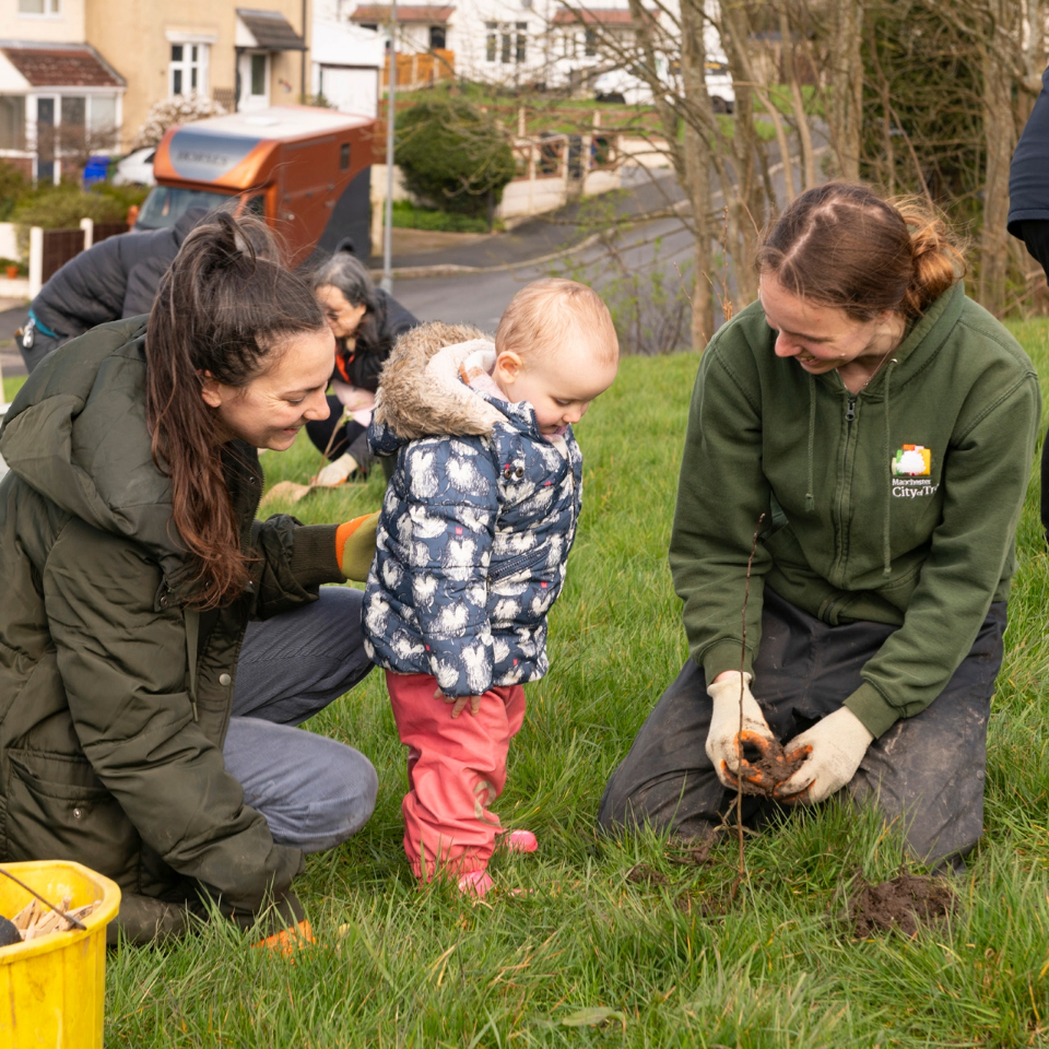 mother and child being shown tree planting by member of city of trees team